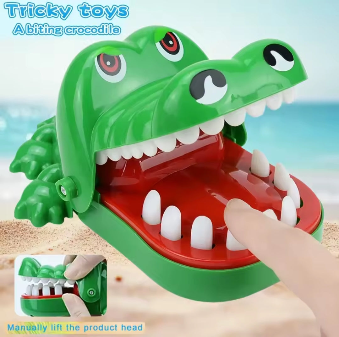 Interactive Crocodile Bite Game featuring a green crocodile with large eyes and sharp teeth; players take turns pressing teeth, avoiding the 'sore tooth' that causes the mouth to snap shut.